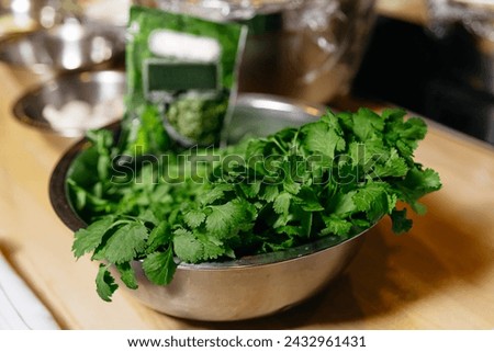 A stainless steel bowl filled with vibrant green cilantro leaves, ready for enhancing flavor in various dishes.