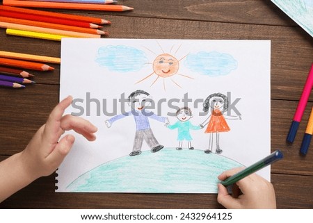 Little boy drawing with pencil at wooden table, top view. Child`s art