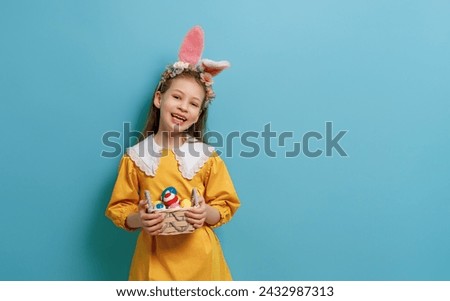 Cute little child wearing bunny ears on Easter day. Girl with painted eggs. Royalty-Free Stock Photo #2432987313