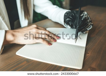 A close-up photo of a A close-up photo of a young disabled girl with a bionic prosthesis writes in a notebook, sitting at a table. Online work, distance learning. The concept of the future, cyborg