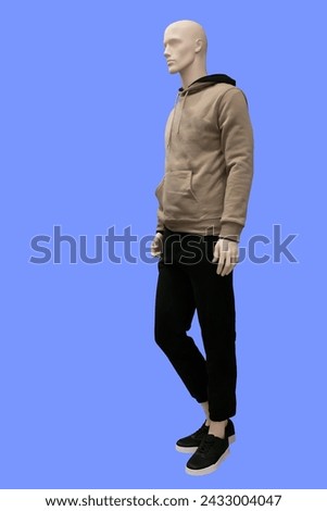Full length image of a male display mannequin wearing light brown hoodie and black jeans isolated on a blue background