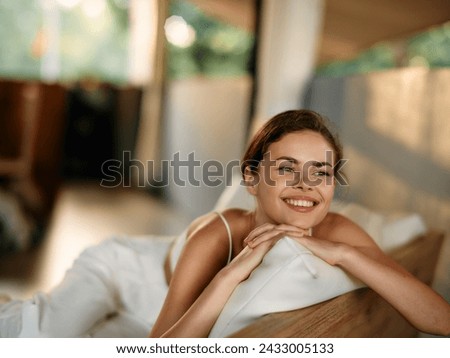 Happy Woman Relaxing on Cozy Sofa at Home, Smiling and Looking at Camera She is Wearing a Warm Sweater and Enjoying Her Free Time The Beautiful Brunette exudes Joy, Contentment, and Beauty in this
