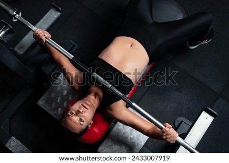 A young woman during a bench press in the gym. Strength training in the gym Royalty-Free Stock Photo #2433007919
