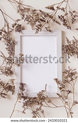 Empty photo frame surrounded by dried flowers on a light background top and vertical view