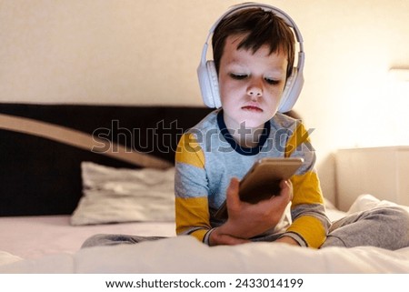 Face of boy, headphones and tablet at night for reading eBook, watch cartoon and play video games on eLearning app. Child, kid and listening to multimedia, music and streaming movies on digital tech.