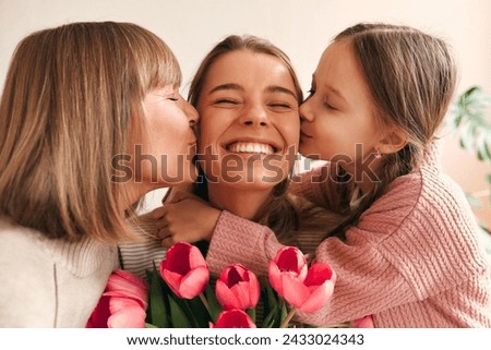 Child and grandmother congratulating and kissing mother and daughter in the living room and giving her flowers. Concept of Women's Day and Mother's Day. Women's generation.