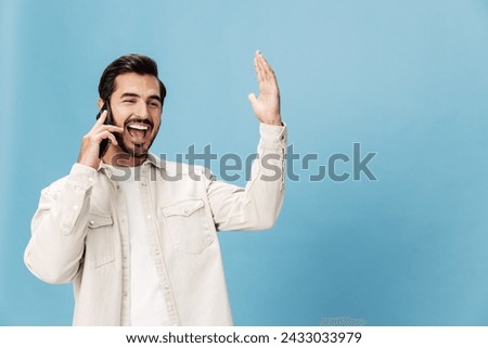 Portrait of a brunette man talking on the phone close-up mobile and internet online, animation open mouth, on a blue background in a white T-shirt, copy space 