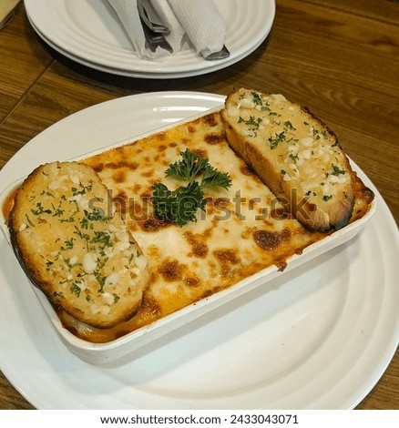 The picture shows a delicious serving of lasagna, a classic Italian dish made with layers of pasta, rich tomato sauce, creamy béchamel sauce, melted cheese, and savory meat such as ground beef or saus