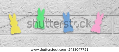 Easter party concept. Banner. Top view photo of garland with easter bunnies on isolated white brick wall background. Holiday header for website, blog, advertisement, flyer.