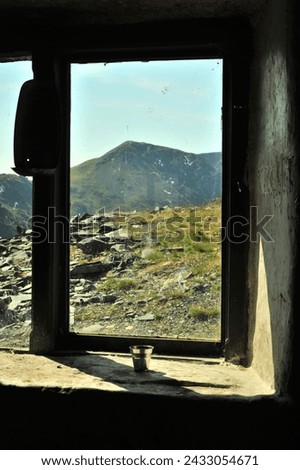 Window of Dubs Hut bothy, a former miners hut located near Fleetwith Pike in the Lake District, UK, with view of High Stile mountain peak above Buttermere lake. Royalty-Free Stock Photo #2433054671