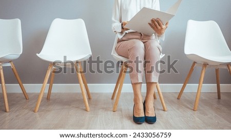 Studio shot of a young businesswoman using a laptop while waiting in line against a gray background. Young woman sitting in lobby with resume in hands and waiting for job interview