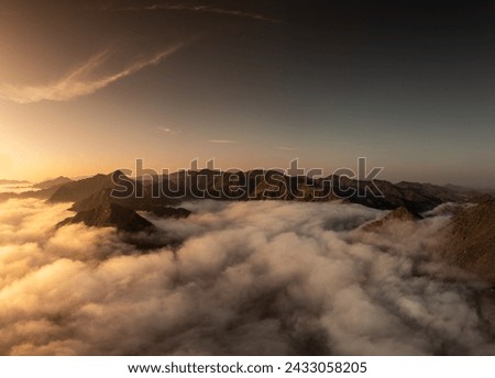 Beautiful views of the sunrise and low clouds hugging the peaks of the Fujairah mountains in the United Arab Emirates Royalty-Free Stock Photo #2433058205