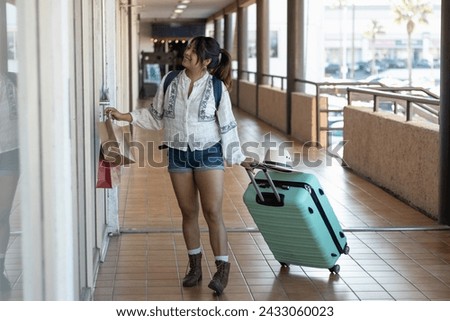 Horizontal photograph of a 26 year old brown skin woman walking downtown with her suitcase during her trip to looking stores and purchase merchandise