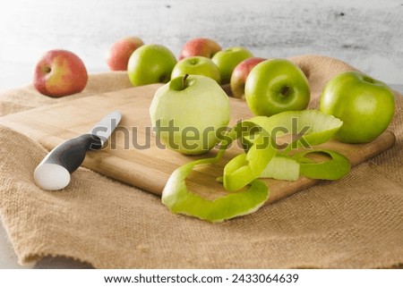 Peeled apple close-up on a cutting board. Red and green apples on a kitchen table
