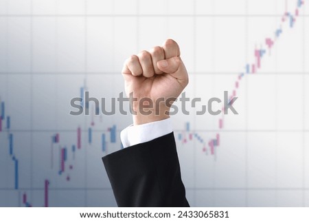 Male fist raised in front of stock chart background