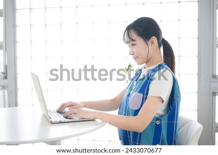 The image of a childcare worker, housekeeper, nanny, or housewife operating a computer. A pretty young Japanese girl with a smile.