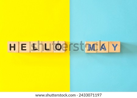 Hello month of May concept. Wooden blocks typography in bright blue and yellow background.	