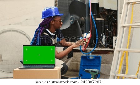 Capable specialist contracted by home owner to detect HVAC system problems, checking real-time superheat and subcooling values measured by manifold gauges displayed on green screen laptop