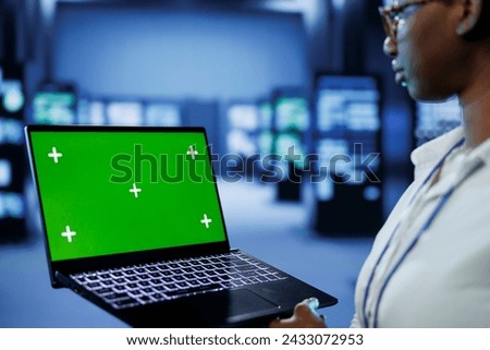 Programmer in server room uses green screen laptop to future proof network from downtimes and unexpected system failures. Tech support with mockup device ensures increased data security
