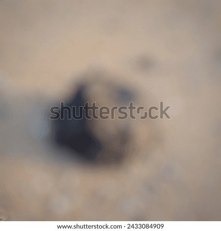 Defocused abstract background of small black coral rocks with messy shapes lie on the beach sand