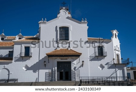 Bathed in the Andalusian sun, the Hermitage of El Rocío stands with its striking white facade and terracotta roofs, a testament to traditional Spanish religious architecture in Huelva.
