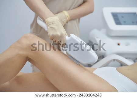 A professional beauty spa offers laser hair removal. A woman undergoes the painless treatment, enhancing smooth, healthy skin. The device is held by a skilled therapist's hand for effective epilation Royalty-Free Stock Photo #2433104245