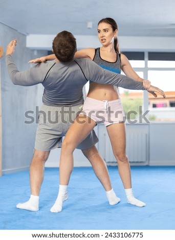 Young woman learning to do power grab on an opponent neck during self-defense training at the gym