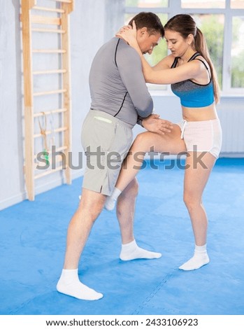 Young woman kicks attacking man - self-defense training in the ring