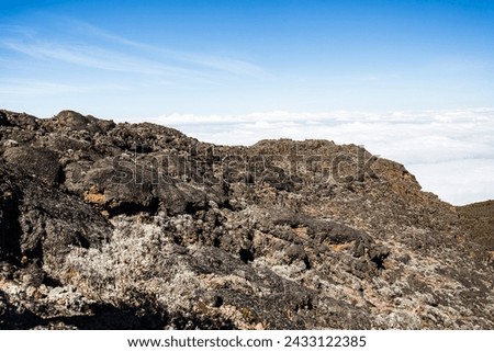 Above the Clouds: Rugged Terrain Meets Endless Sky Royalty-Free Stock Photo #2433122385