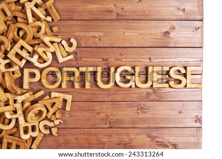 Word portuguese made with block wooden letters next to a pile of other letters over the wooden board surface composition