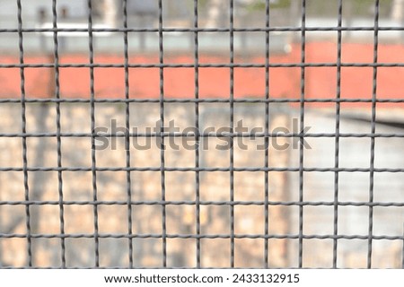 metal border separation mesh and the building wall intentionally blurred in the background Royalty-Free Stock Photo #2433132915