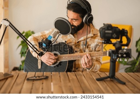 man at home playing guitar with microphone and headphones influencer recording, podcast blogger
