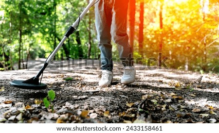 A boy in the park with a metal detector is looking for treasure. High quality photo
