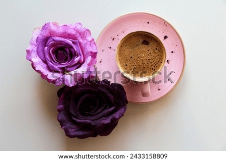 Turkish coffee in pink coffee cup next to purple and plum flowers