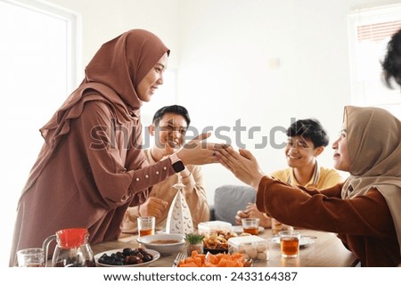 Two muslim women handshaking and greetings to each other during Eid mubarak celebration Royalty-Free Stock Photo #2433164387