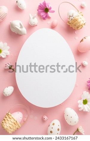 Classy Easter motif picture. Vertical top view shot of eggs, lively chrysanthemums, ceramic bunnies on a light pink base, with open egg-shaped spot for messages or marketing