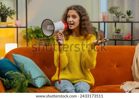 Child girl talking with megaphone, proclaiming news, loudly announcing advertisement warning using loudspeaker to shout speech. Teenager female 14-15 years kid at home living room apartment on sofa Royalty-Free Stock Photo #2433173511
