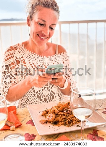 One pretty adult woman taking picture of her food before eating lunch. Pasta spaghetti with fish. Modern female people photograph lunch using mobile phone to share online content creator lifestyle