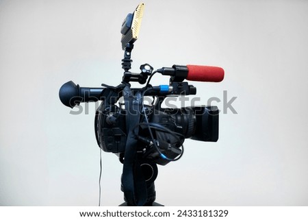 Professional video camera. Camera lens, bokeh background. Professional equipment for the production of video content. Shooting a news report. Journalism. Focusing lens of a video camera.