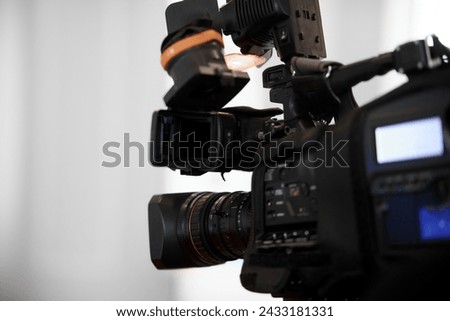 Professional video camera. Camera lens, bokeh background. Professional equipment for the production of video content. Shooting a news report. Journalism. Focusing lens of a video camera.