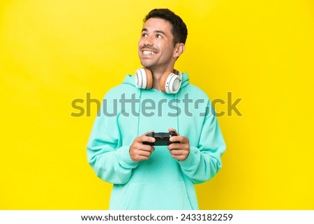 Young handsome man playing with a video game controller over isolated wall thinking an idea while looking up