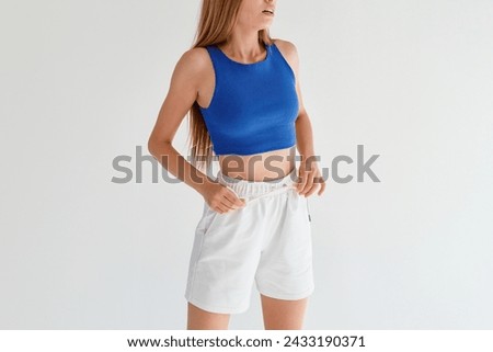 Front view of a Woman wearing a crop top. Horizontal studio photo on white neutral background. Girl posing in blank shirt.