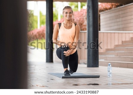 Attractive woman doing stretching exercises outdoors. Woman stretching ham strings before a run. Woman stretching at park while listening to music. Young woman working out at sunset. 