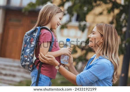 Mother accompanies the child to school. Mom supports and motivates the student.caring mother gently kisses her daughter on the forehead. Positive little girl fun going to primary school.Back to school