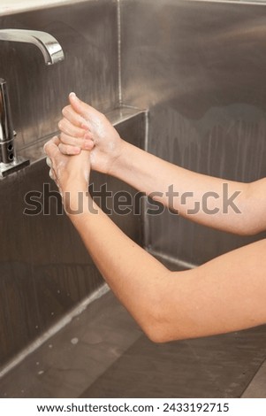 Surgeon having his hands surgically washed. A Caucasian doctor dressed in his right-hand profile with his hands full of foam and dressed in his surgical uniform.	 Royalty-Free Stock Photo #2433192715