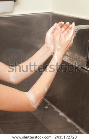 Surgeon having his hands surgically washed. A Caucasian doctor dressed in his right-hand profile with his hands full of foam and dressed in his surgical uniform.	 Royalty-Free Stock Photo #2433192723