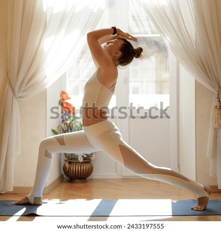 Fitness woman in white sportswear doing yoga near the balcony in the morning.