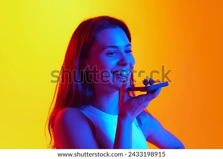 Close-up photo of young woman talking on phone and smiling against gradient yellow background in vibrant neon light, Concept of human emotions, youth culture, self-expression, technology. Ad