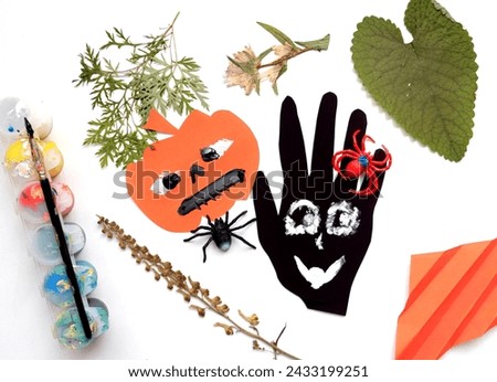 Child making for the holiday of Halloween. Funny crafts from paper and natural dry plants. Halloween decor. DIY.