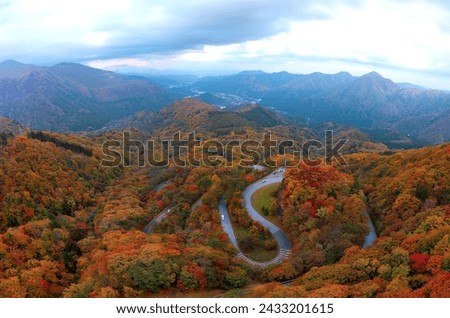 Top down view over Irohazaka (いろは坂, a scenic mountain highway connecting Lake Chuzenji to Nikko City, in Tochigi Prefecture, Japan), with multiple hairpin turns winding through colorful autumn forests Royalty-Free Stock Photo #2433201615